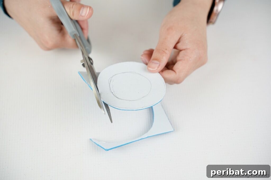 DIY Painted Tin Can Snowman Video Tutorial 16 Hands carefully cutting out the inner circle of a foam paper ring, forming the brim of a snowman's hat.
