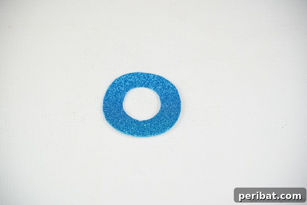 DIY Painted Tin Can Snowman Video Tutorial 17 A neatly cut blue hat brim made from foam paper, ready to be attached to the snowman's hat.