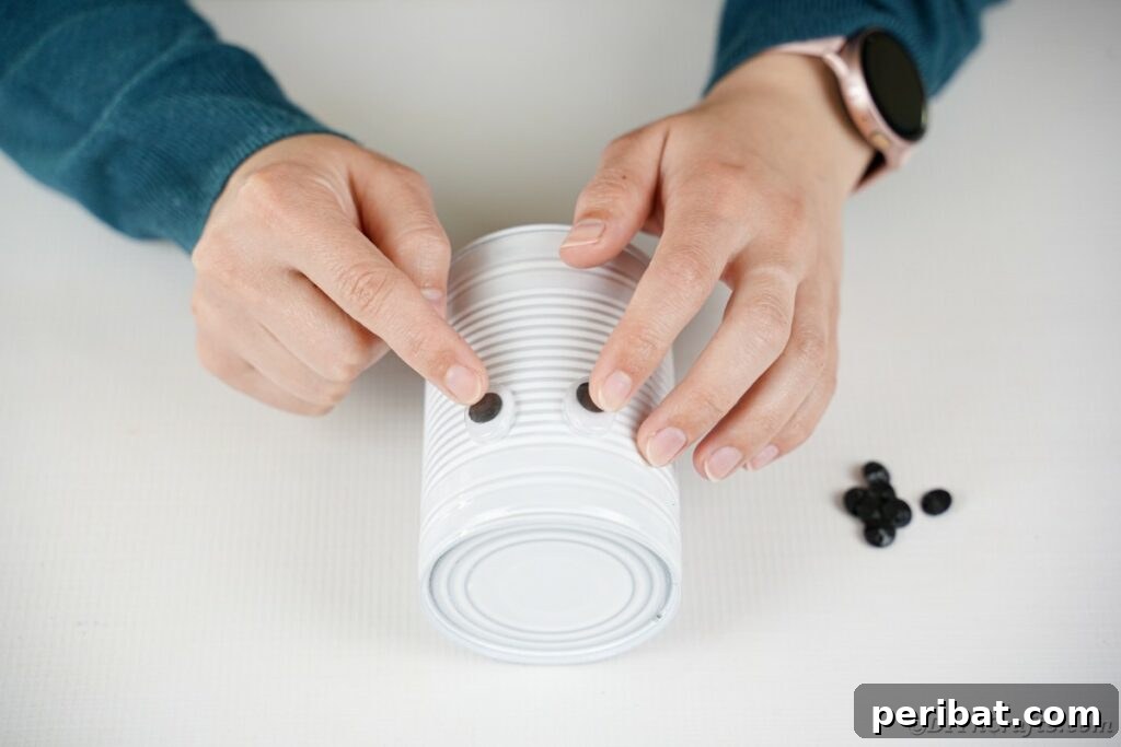 DIY Painted Tin Can Snowman Video Tutorial 19 Carefully attaching googly eyes to the painted tin can that will form the snowman's head.