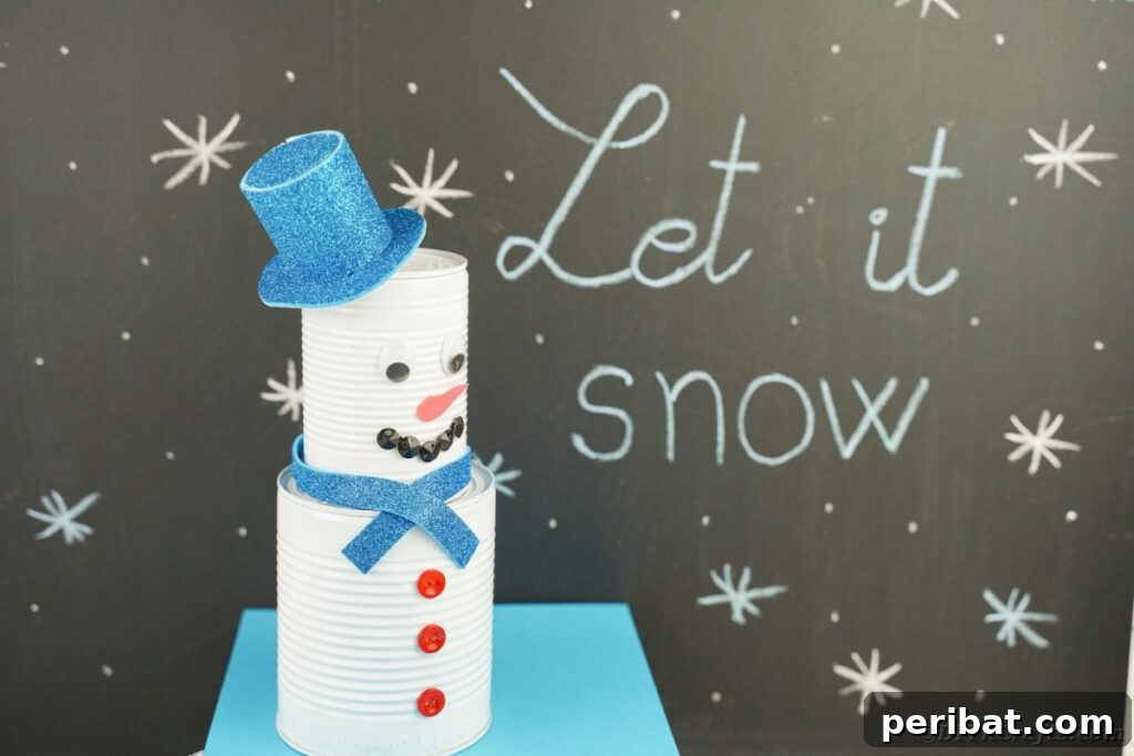 DIY Painted Tin Can Snowman Video Tutorial 4 A whimsical tin can snowman decoration posing cheerfully beside a chalkboard, showcasing its handcrafted details.
