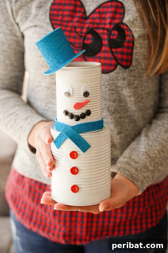 DIY Painted Tin Can Snowman Video Tutorial 5 A person proudly holding a finished tin can snowman, showcasing its handmade charm and potential for personalization.