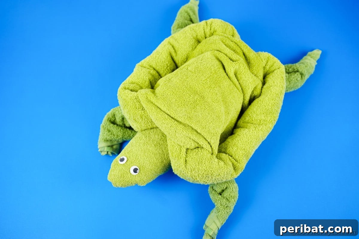 Towel Origami: Animal Edition 14 Green turtle towel with googly eyes on a blue table
