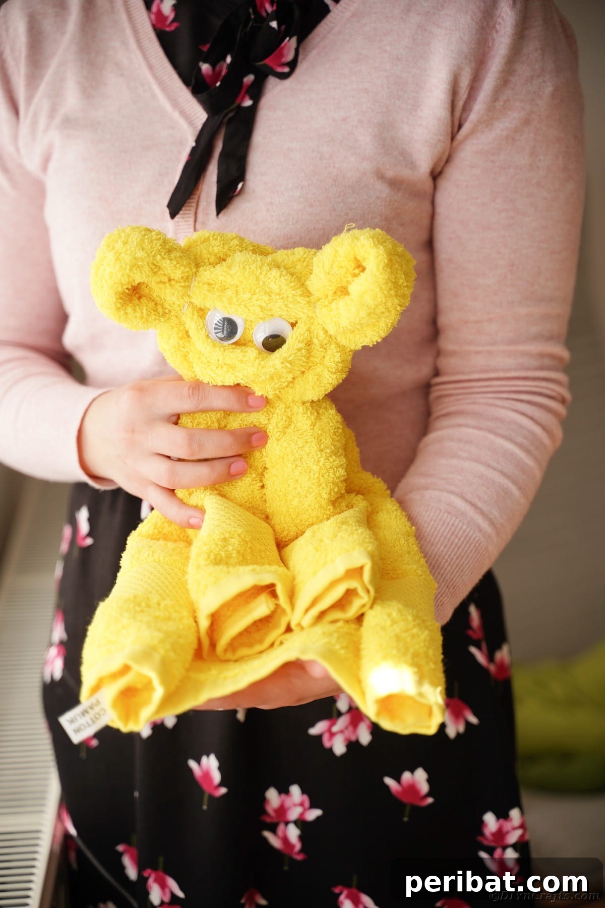 Towel Origami: Animal Edition 15 Woman holding a yellow bear towel, showcasing a finished project