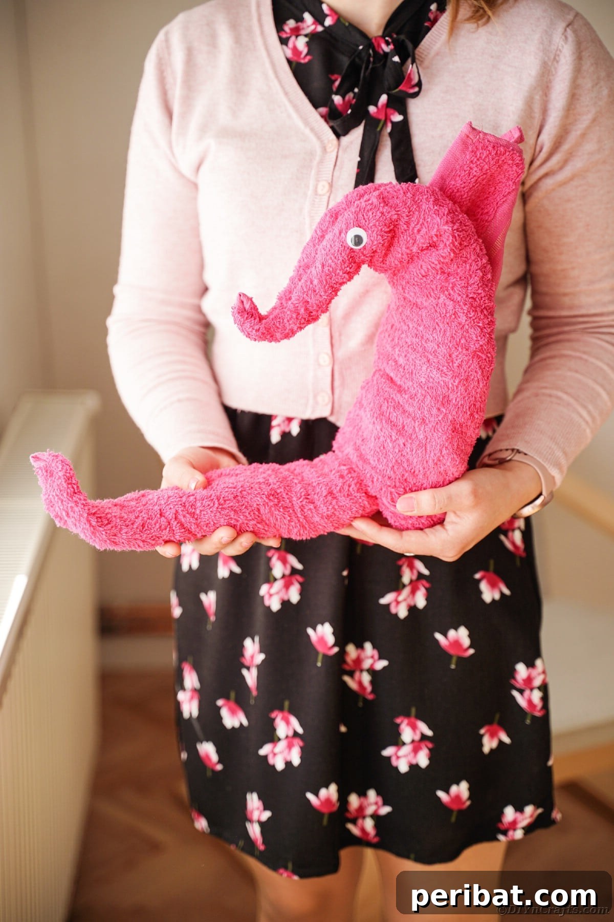 Towel Origami: Animal Edition 18 Woman holding a pink seahorse towel, a whimsical decoration
