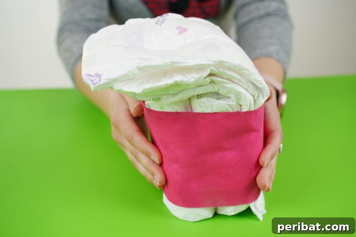 Create a Charming Diaper Train for Baby Shower Joy 18 Tissue paper being wrapped around the base of the diaper engine, neatly secured with glue for a polished appearance.
