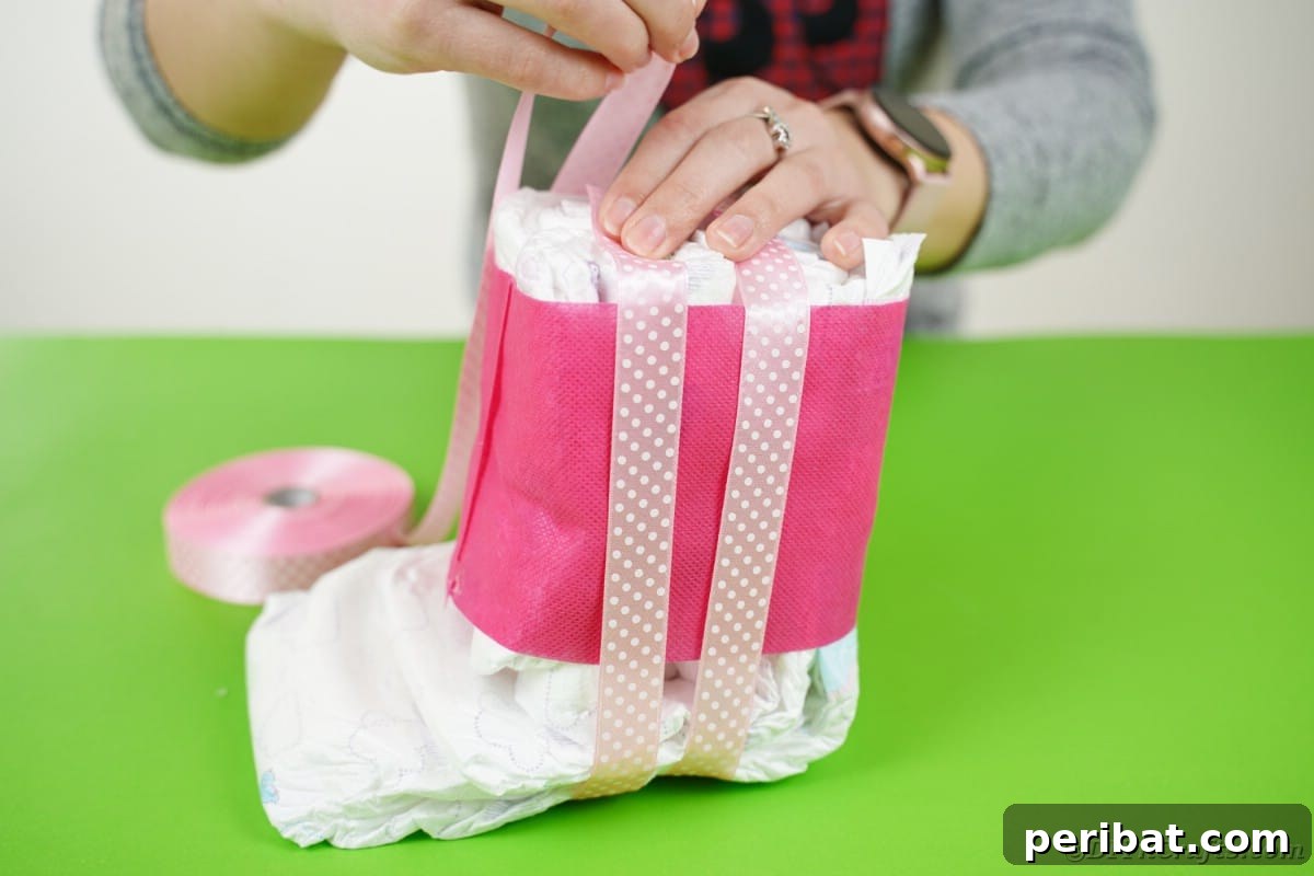 Create a Charming Diaper Train for Baby Shower Joy 19 A decorative ribbon being carefully added to the top of the diaper engine bundle, secured with glue for a finished look.