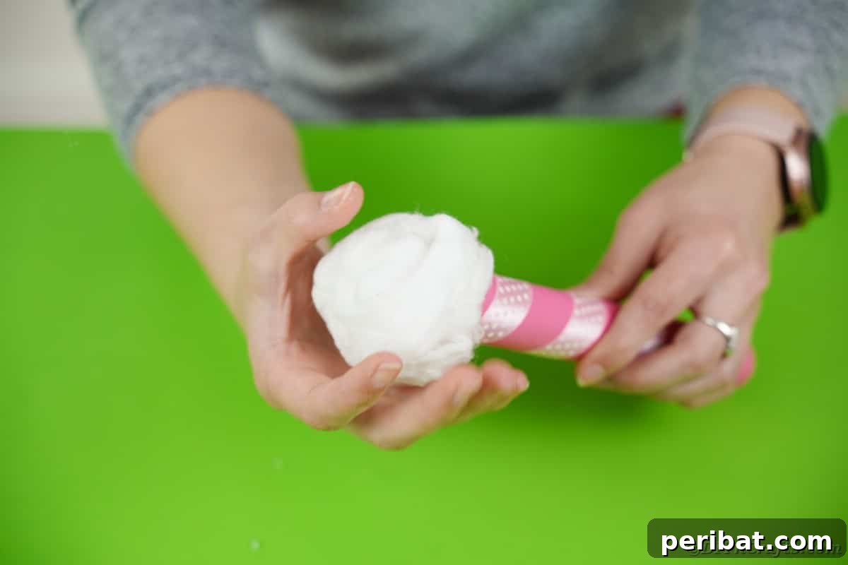 Create a Charming Diaper Train for Baby Shower Joy 24 Cotton balls being added to the top of the decorated tube, creating the whimsical 'smoke' effect for the train.