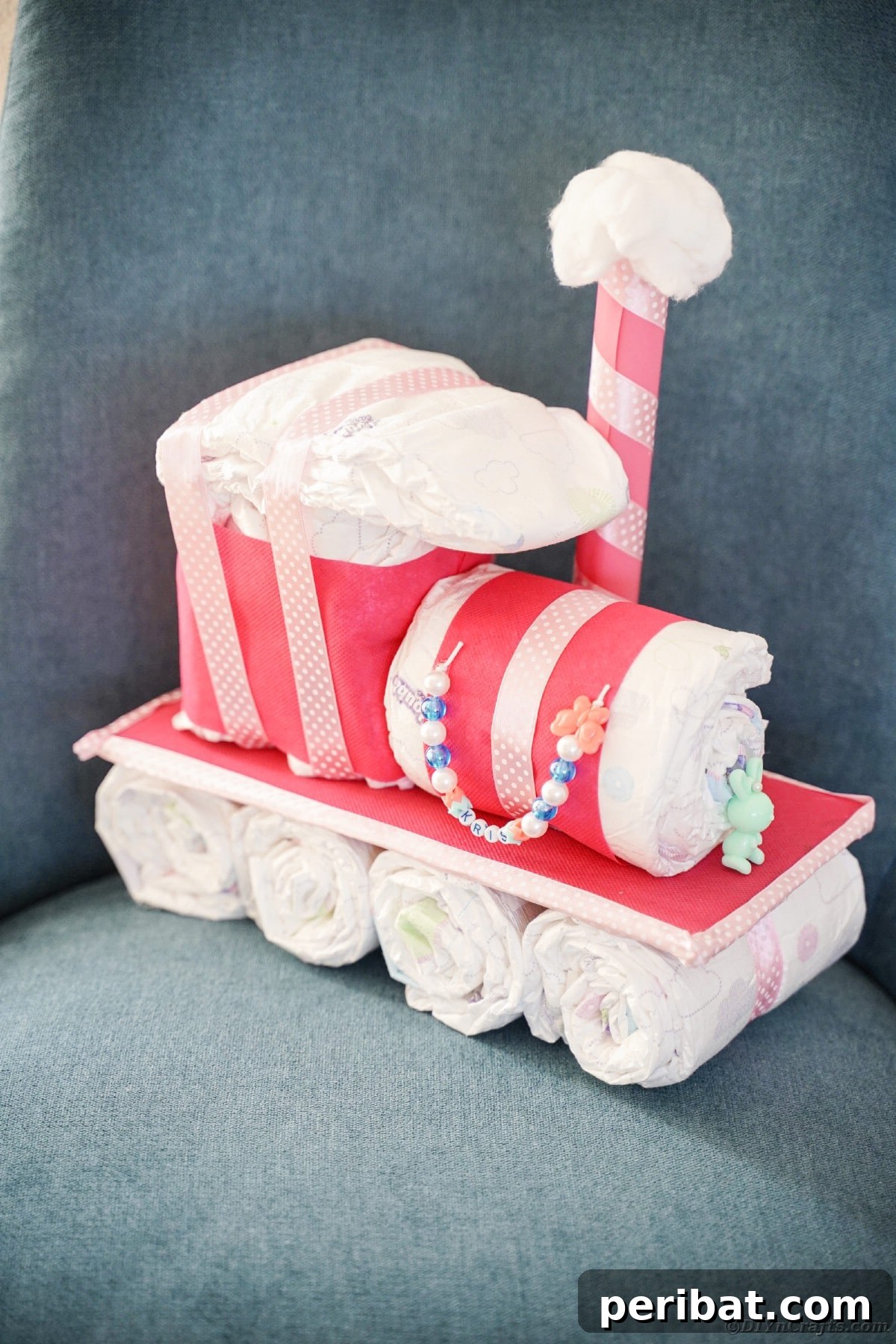Create a Charming Diaper Train for Baby Shower Joy 29 A beautifully crafted diaper cake train resting on a cozy chair, showcasing a unique display option for a nursery or gift.