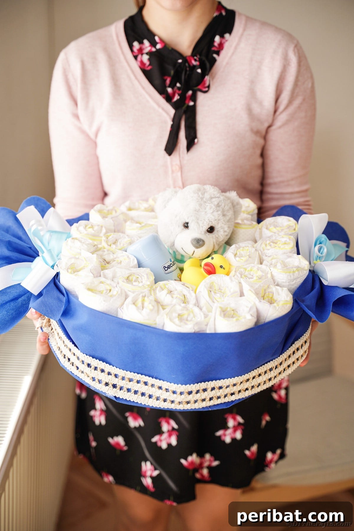 A woman proudly displaying her completed candy wrapper diaper cake, a perfect blend of a gift and a charming decoration.