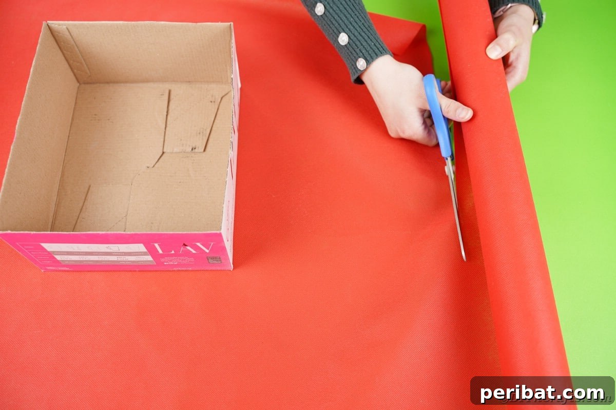 Charming Diaper Bassinet: A Perfect Baby Shower Present 8 Cutting vibrant red tissue paper to prepare for wrapping the cardboard boxes, the first step in creating a diaper cake bassinet.