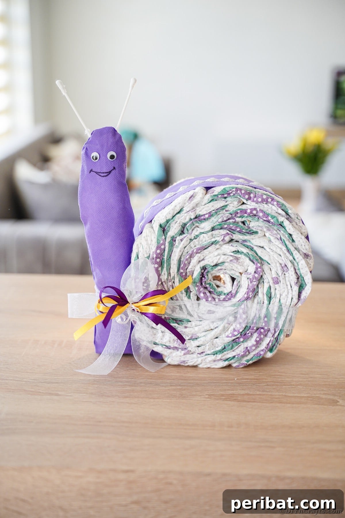 Several snail diaper cakes arranged artfully on a warm wooden table, showcasing a delightful family of snails as a collective baby gift display.