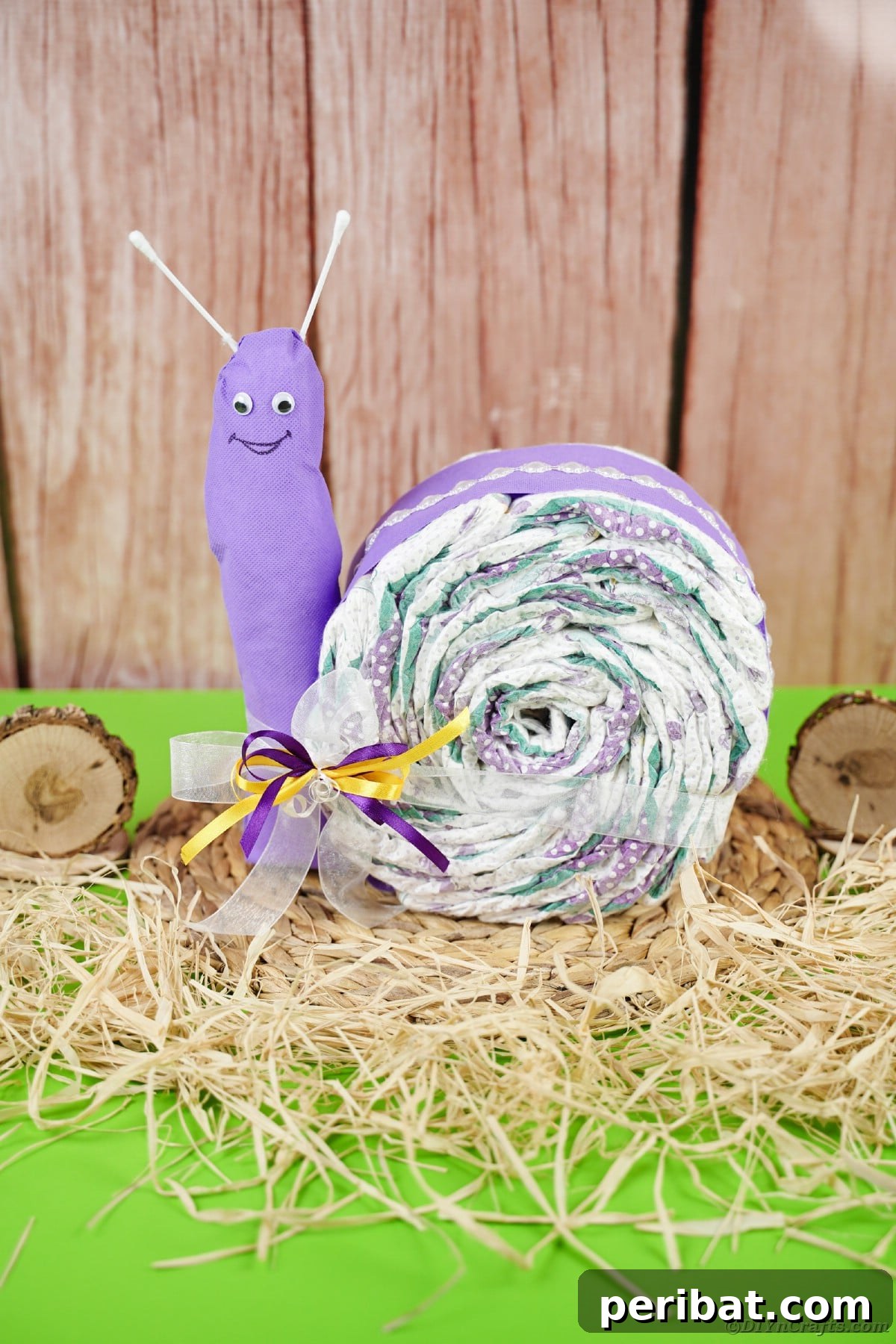 A personalized snail diaper cake adorned with a miniature straw hat, nestled amongst hay, perfect for a rustic or garden-themed baby shower.