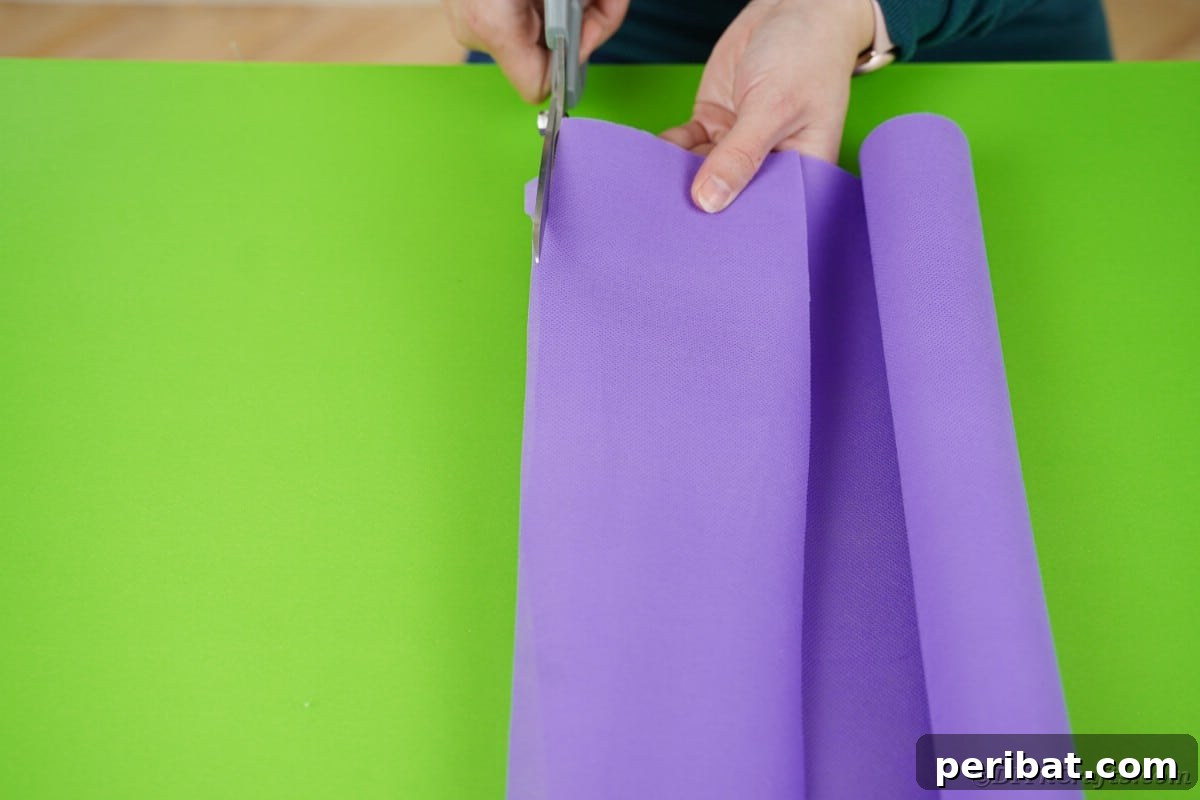 Hands meticulously cutting purple fabric, shaping it into the distinctive form that will become the snail's neck and head.