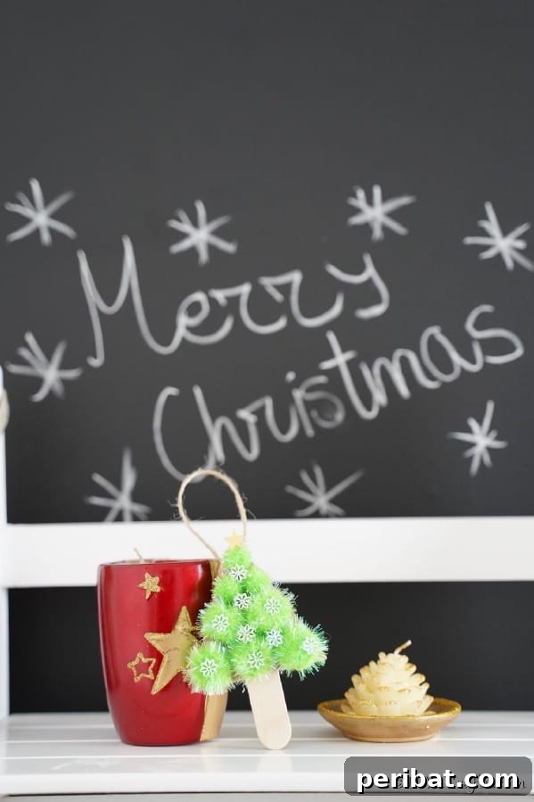 40 Christmas Craft Ideas to Spark Kids' Creativity This Winter Break 4 A charming Christmas pom-pom tree ornament standing beside a chalkboard, made from craft sticks and colorful pom-poms.