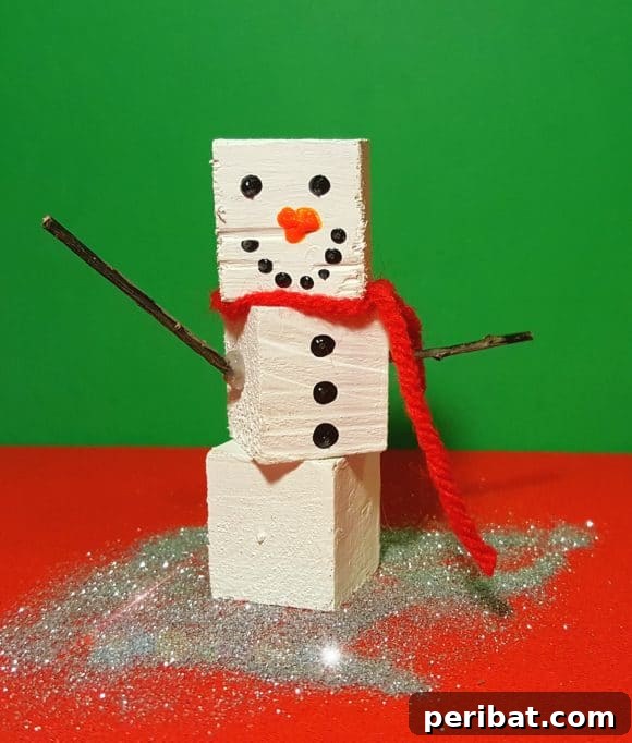 40 Christmas Craft Ideas to Spark Kids' Creativity This Winter Break 34 A festive painted block snowman craft displayed on a red table, showcasing an easy and fun holiday character project for kids.