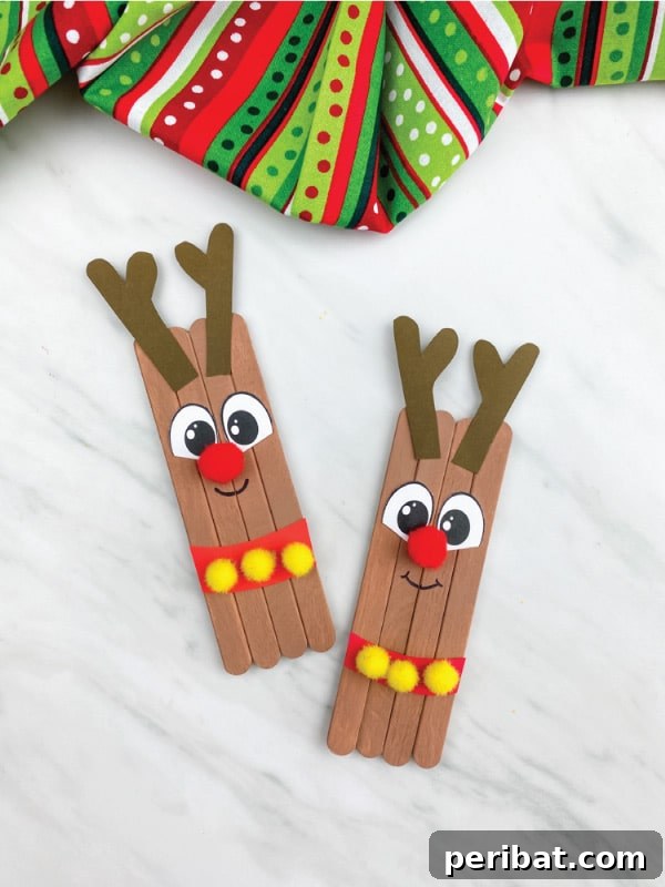 40 Christmas Craft Ideas to Spark Kids' Creativity This Winter Break 39 A festive popsicle stick reindeer kids' craft ornament displayed on a table, complete with a template for easy creation.