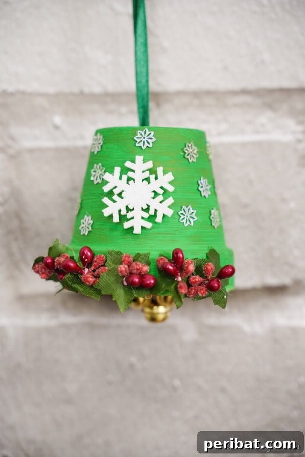 40 Christmas Craft Ideas to Spark Kids' Creativity This Winter Break 7 A charming DIY Christmas bell decoration made from an inverted flower pot, adorned with festive winter and holiday stickers.
