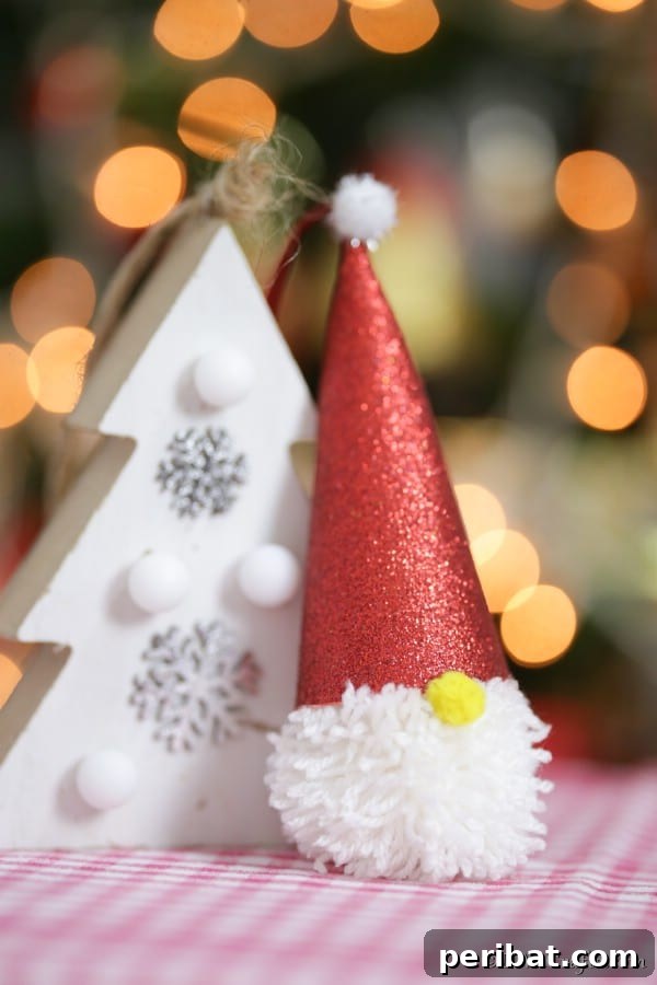 40 Christmas Craft Ideas to Spark Kids' Creativity This Winter Break 10 An adorable pom-pom gnome ornament gently leaning on a Christmas tree branch, adding a whimsical and rustic touch to holiday decor.