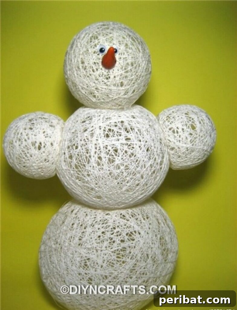 A large, whimsical snowman crafted from cotton thread wrapped around balloons, creating a delicate, airy structure, with a small hat and scarf.