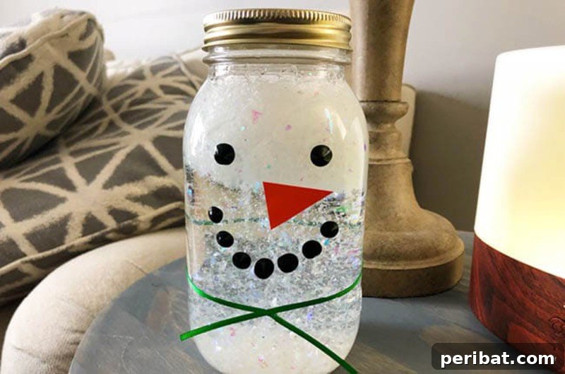 A clear glass jar transformed into a snowman sensory jar, filled with white sensory materials and snowman facial features, designed for engaging play.