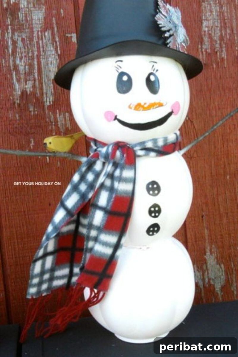 A creative upcycled snowman crafted from a plastic Halloween pumpkin bucket, painted white and decorated with snowman features, ready for winter display.