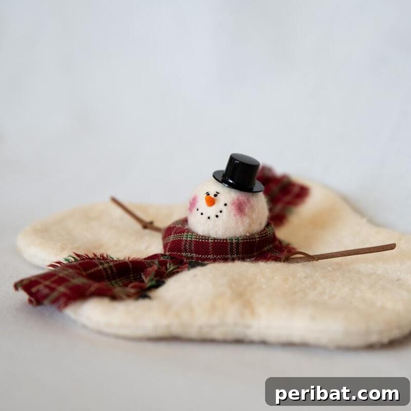 A unique melted snowman craft made from fuzzy white fabric, arranged to look like a puddle with a snowman's hat, scarf, and carrot nose detached, creating a humorous effect.