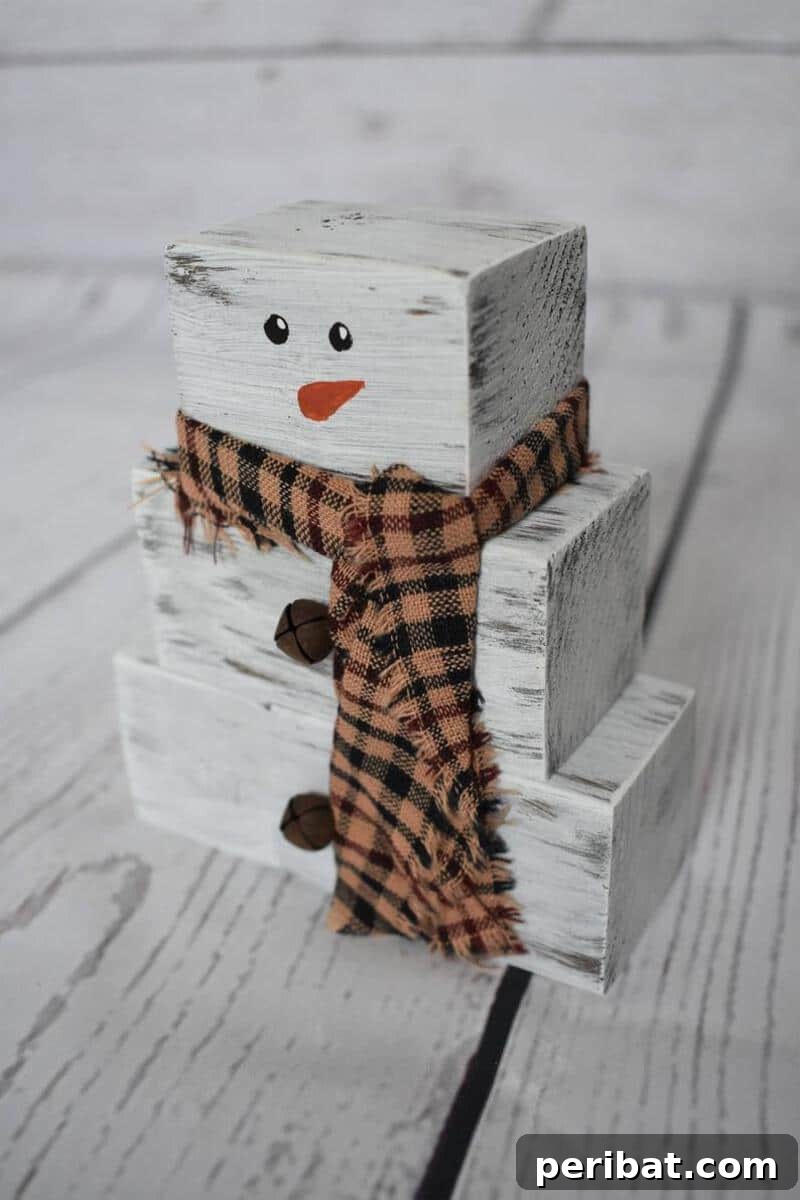 A whimsical stacked block snowman decoration, crafted from painted wooden blocks adorned with a top hat, scarf, and festive winter embellishments, ideal for home decor.