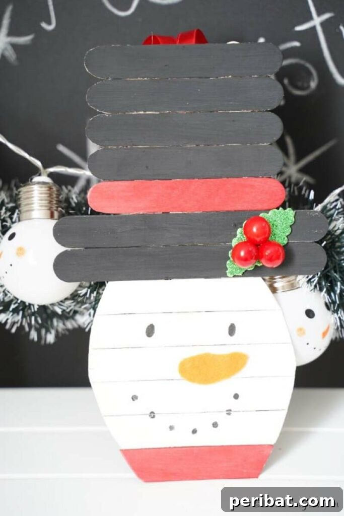 A group of smiling snowmen crafted from painted popsicle sticks, adorned with small hats and scarves, suitable for DIY winter decorations.