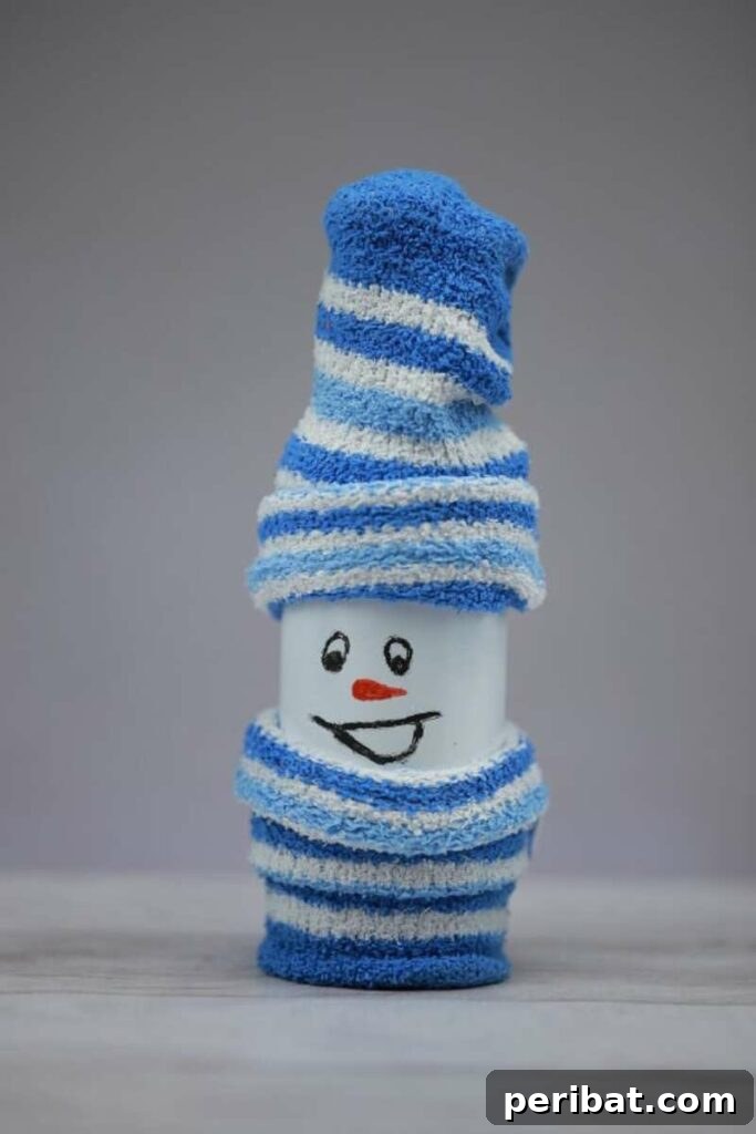 An adorable snowman crafted from an upcycled bottle covered with a fuzzy white sock, adorned with buttons and a small scarf.