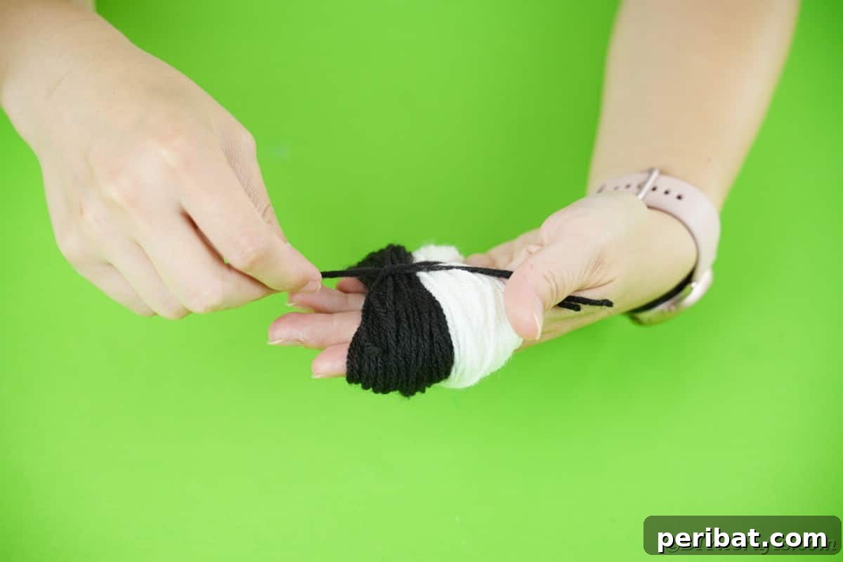 Handmade Pom Pom Penguin Winter Charm 11 Yarn bundles being tied in the center to create a two-toned pom pom