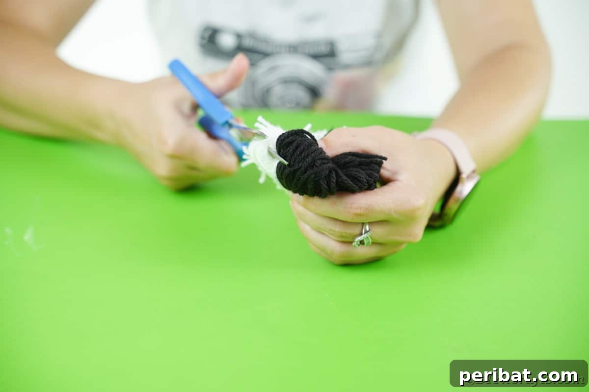 Handmade Pom Pom Penguin Winter Charm 12 Cutting the loops of yarn to form a pom pom