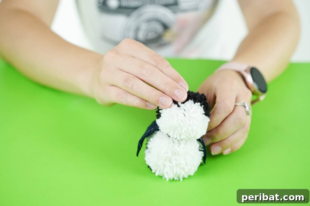 Handmade Pom Pom Penguin Winter Charm 17 Attaching the second pom pom to form the penguin's head and body