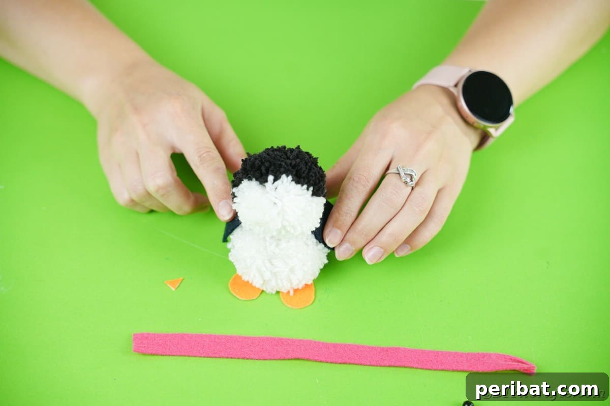 Handmade Pom Pom Penguin Winter Charm 18 Adding orange foam paper feet to the pom pom penguin