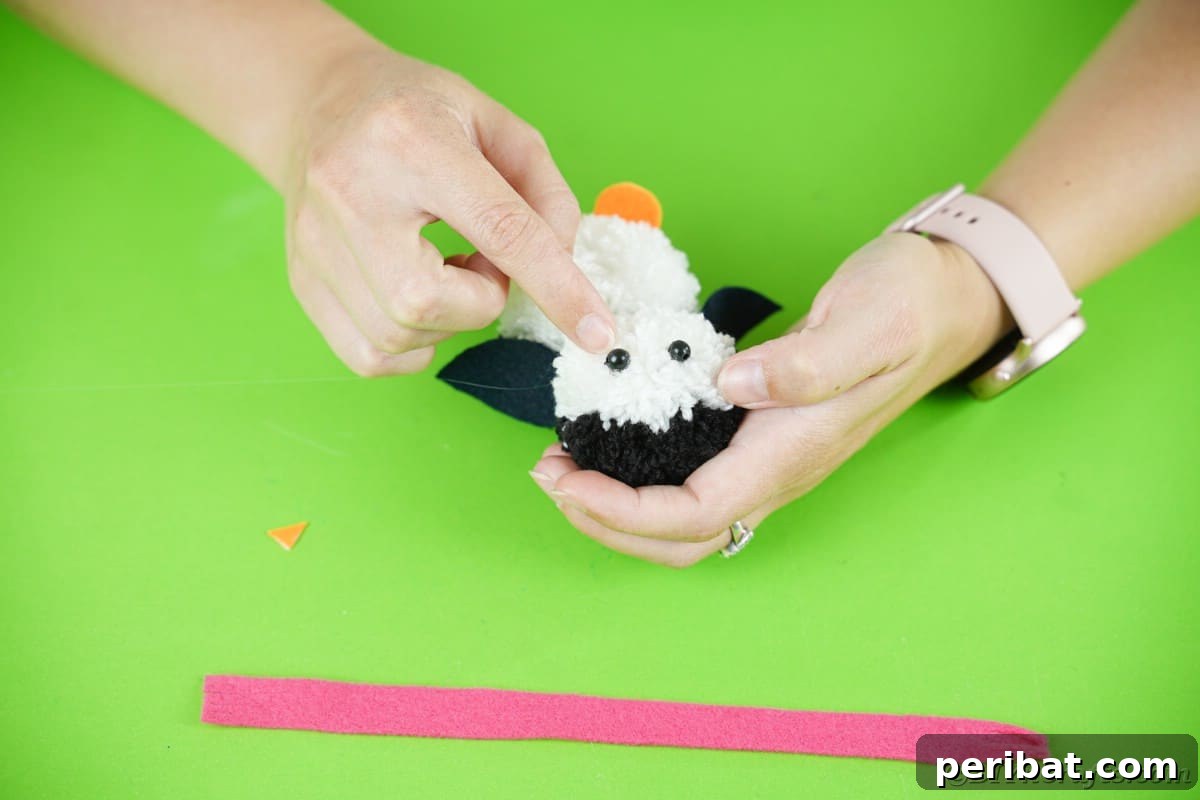 Handmade Pom Pom Penguin Winter Charm 19 Gluing black bead eyes onto the pom pom penguin's head