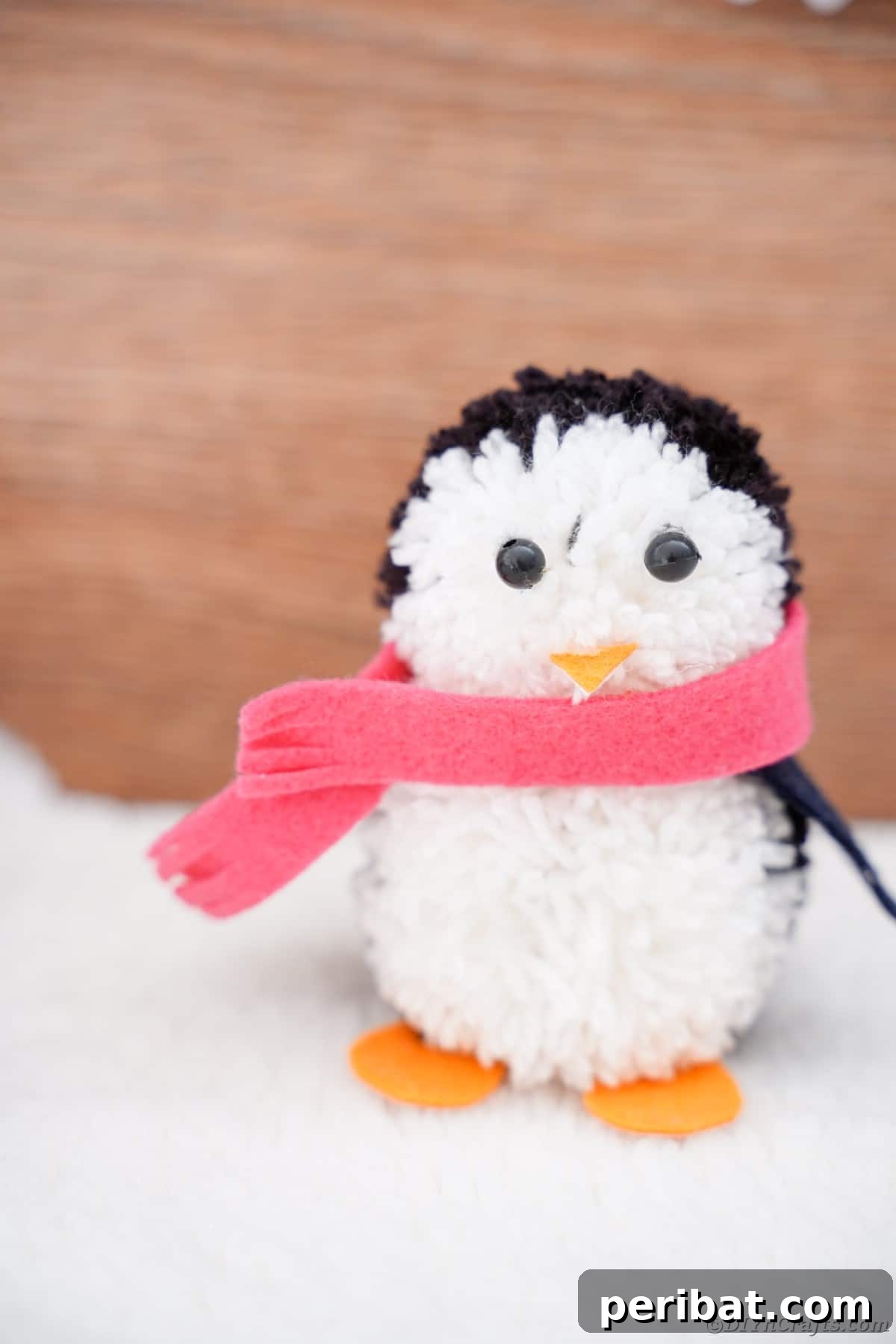Handmade Pom Pom Penguin Winter Charm 22 Finished pom pom penguin decoration sitting on a snowy surface