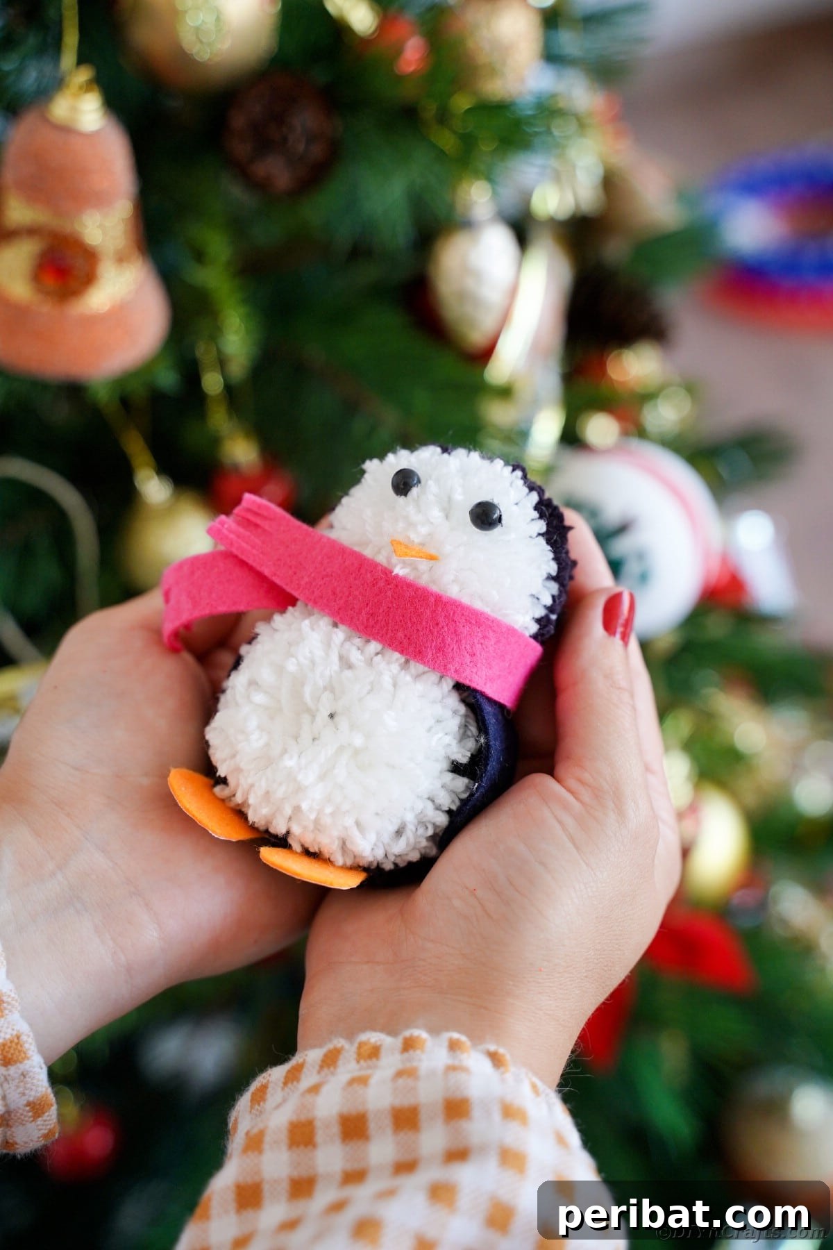Handmade Pom Pom Penguin Winter Charm 24 Woman's hand holding a finished pom pom penguin decoration