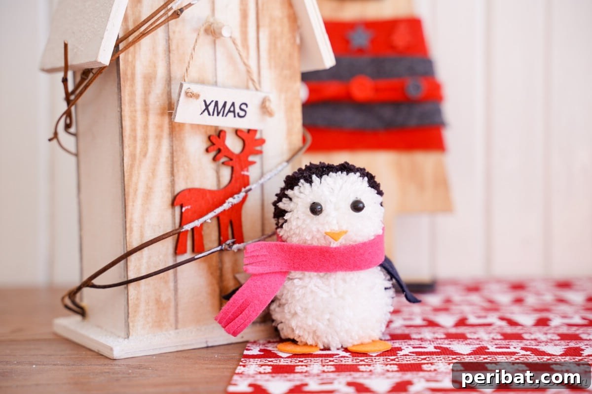 Handmade Pom Pom Penguin Winter Charm 5 Two finished pom pom penguins on wooden winter decor