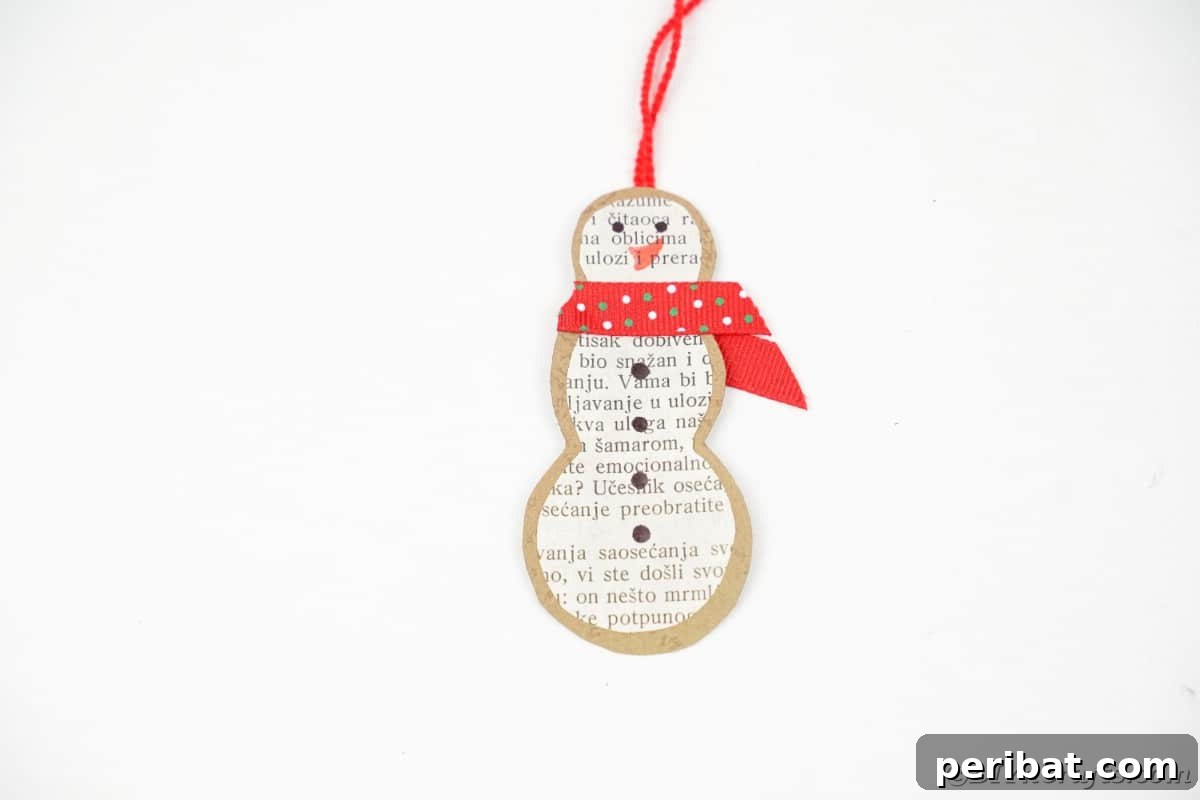 Vintage Book Page Snowman Ornament 16 Finished paper snowman ornament ready for hanging on a white surface