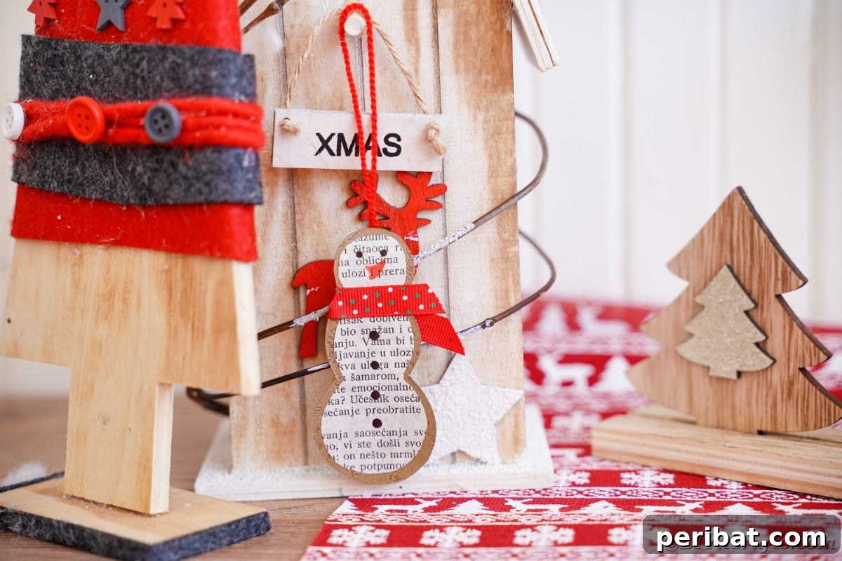 Vintage Book Page Snowman Ornament 5 Completed paper snowman ornament with a red ribbon scarf next to holiday decorations