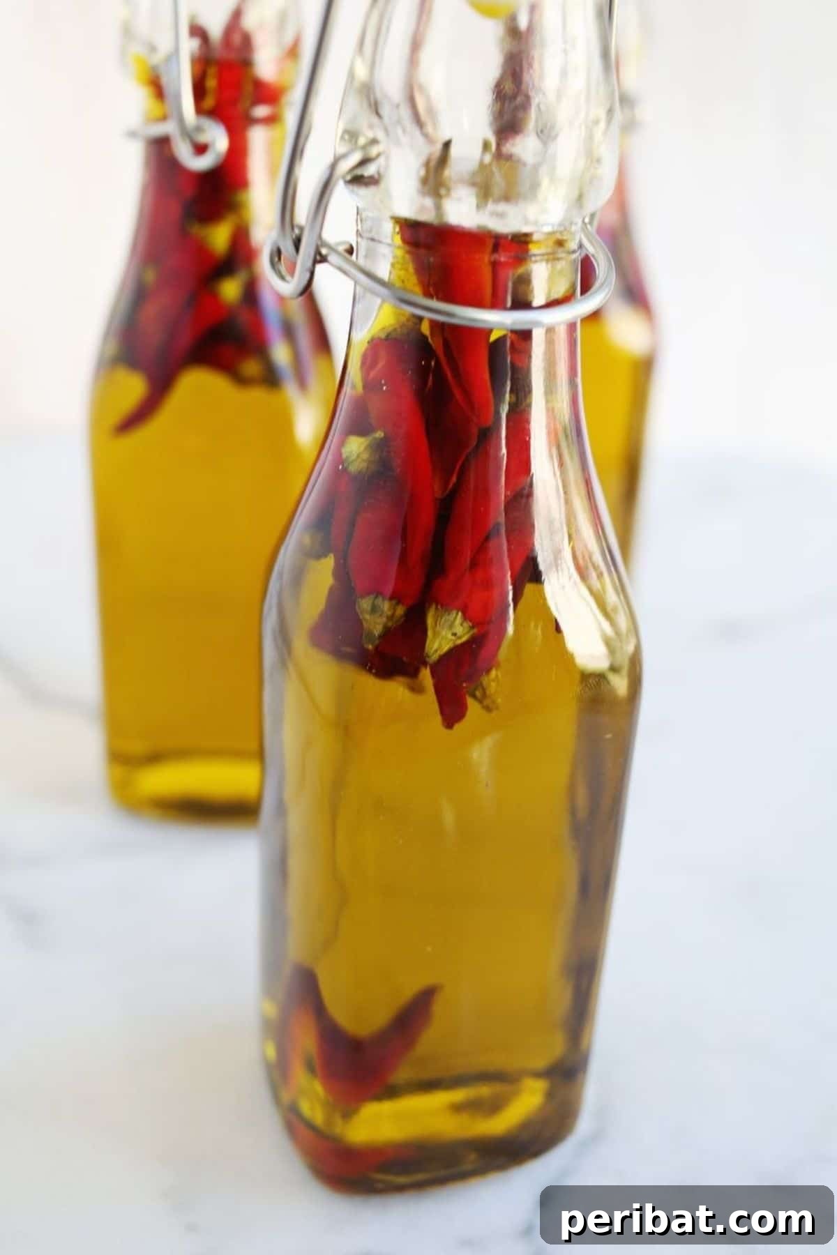 Bottles of homemade hot pepper oil infused with red chili flakes, a perfect gift for spice lovers.