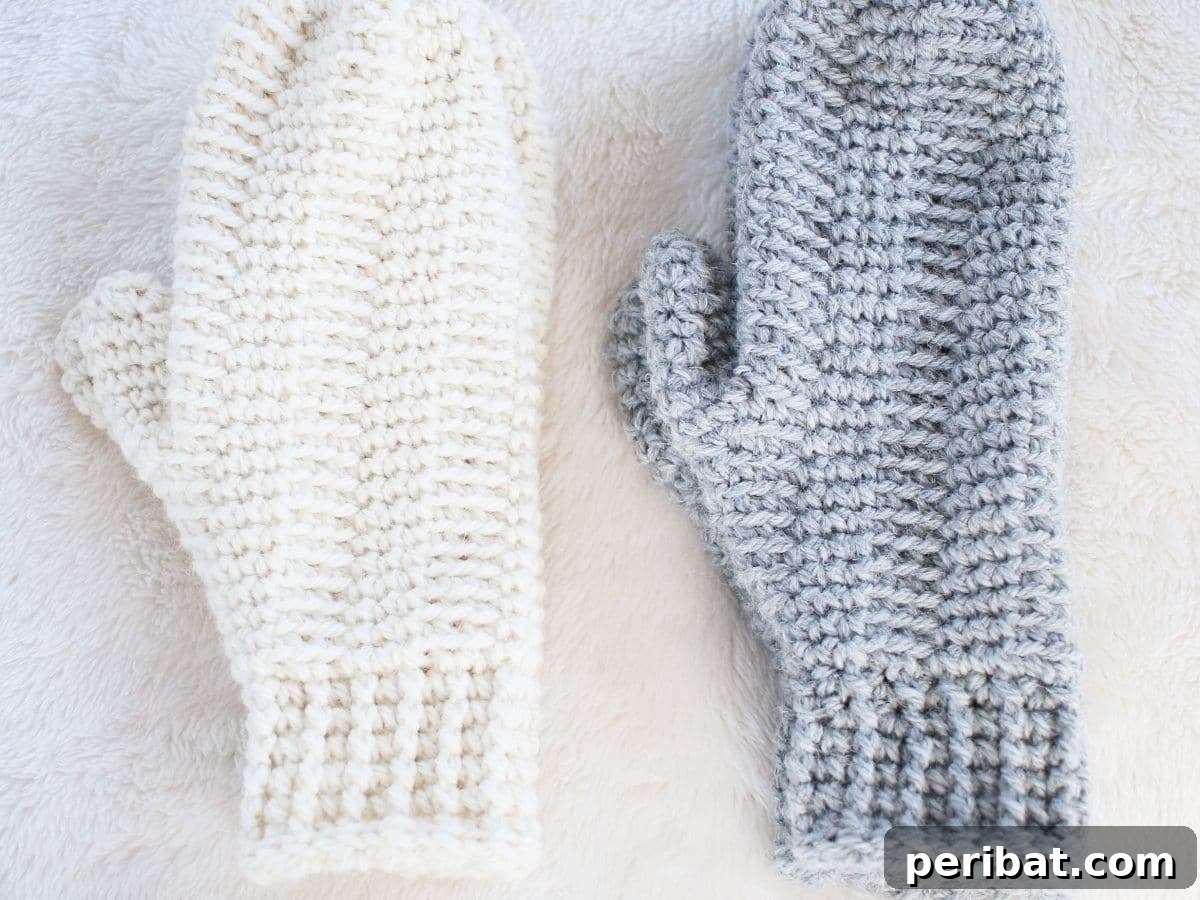 A pair of warm, handmade crochet mittens in a neutral color, perfect for cold weather.
