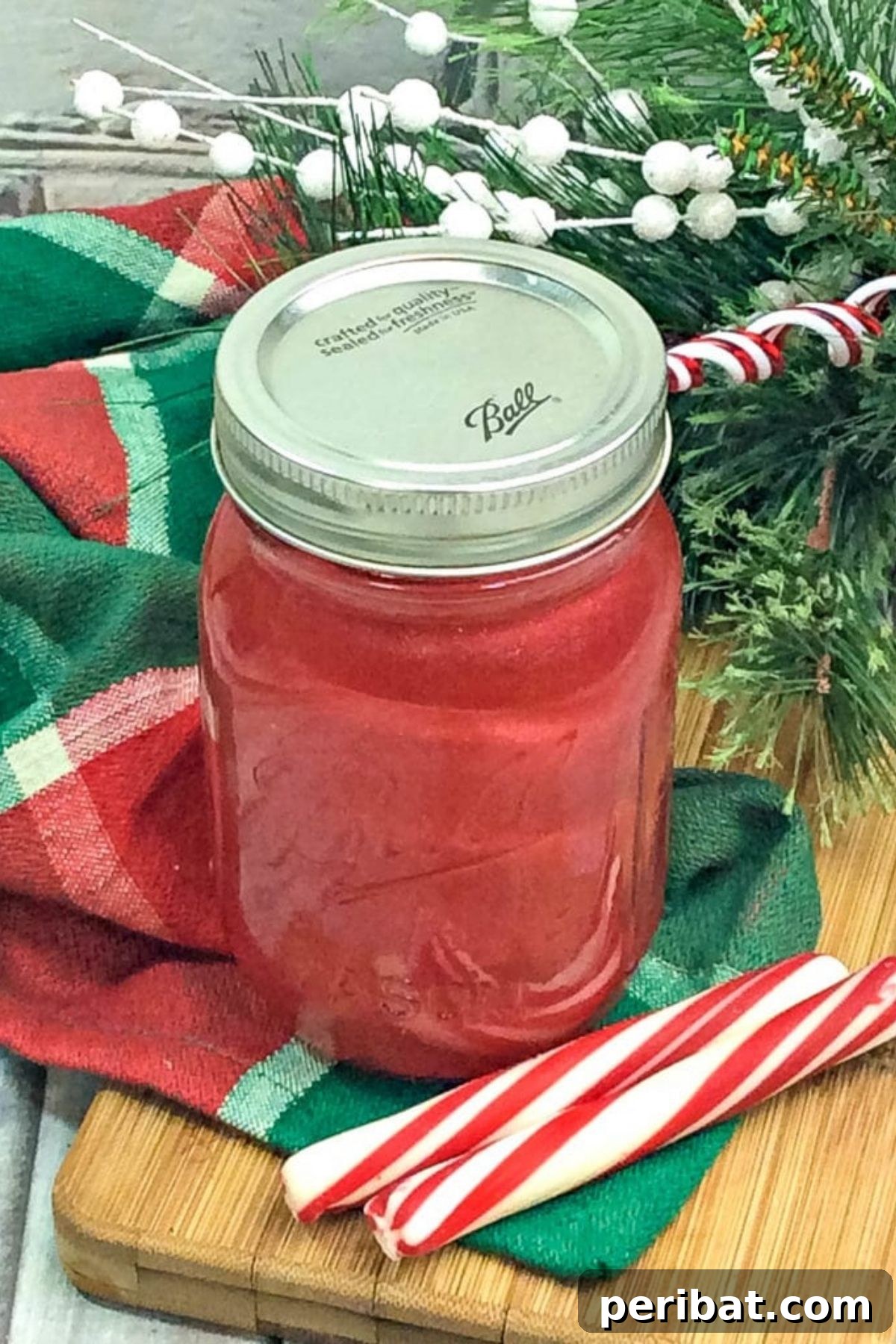A mason jar filled with festive pink candy cane moonshine, a unique homemade beverage gift.