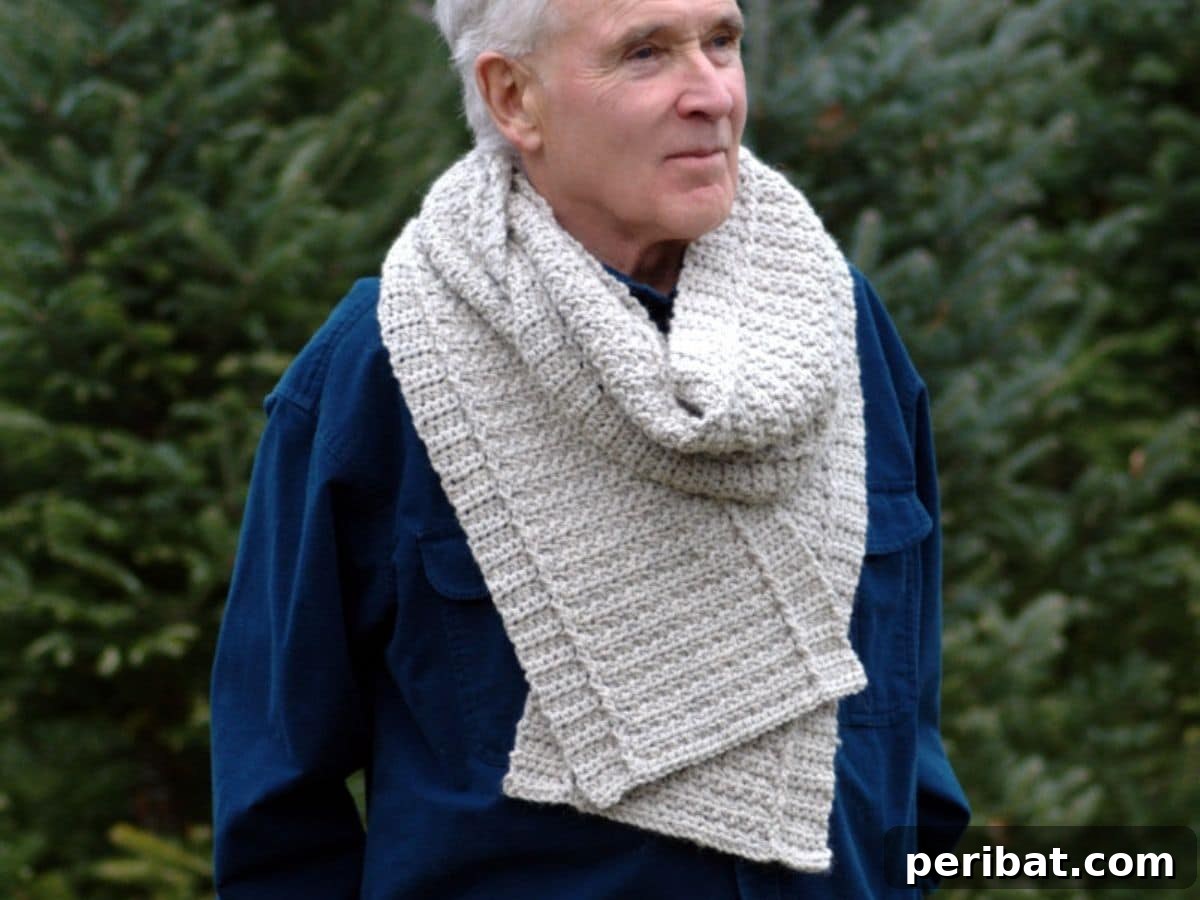 A man wearing a long, thick, and cozy crocheted scarf in a grey hue, ideal for winter.