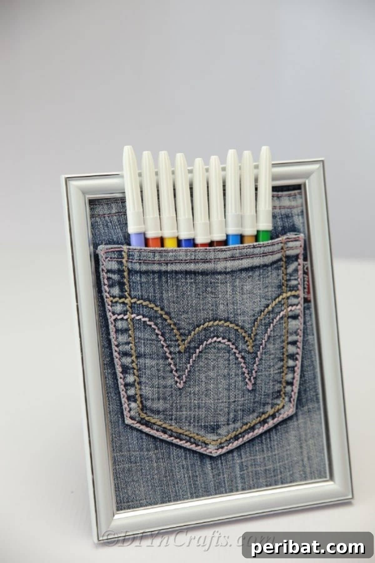 A unique jean pocket organizer framed for display, offering a practical and stylish DIY storage solution for pens, pencils, and other small items in a child's room.