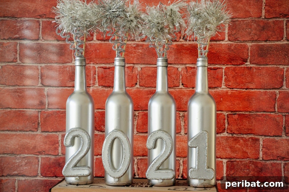 Close-up of three silver-painted wine bottles with New Year's numbers against a rustic red brick background.