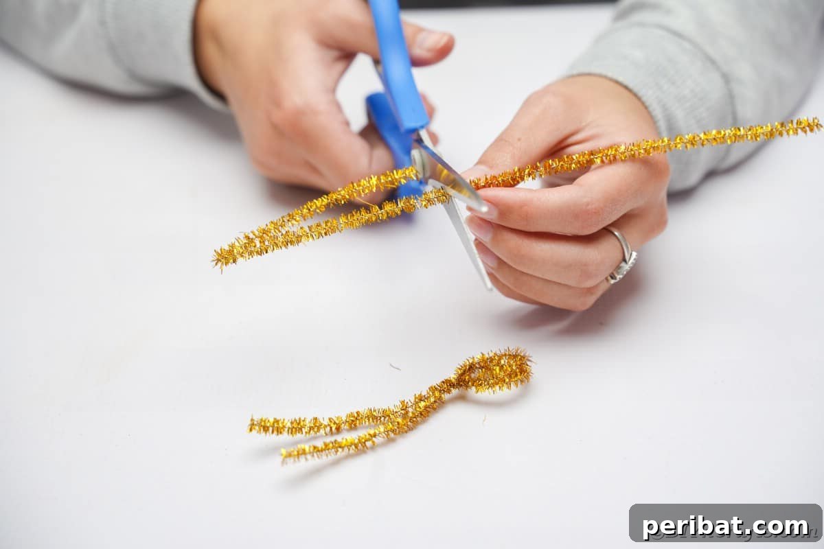 Twist Up a Dazzling Pipe Cleaner Fireworks Ring 10 A pair of hands using scissors to cut a second pipe cleaner into two equal halves, preparing for the next step