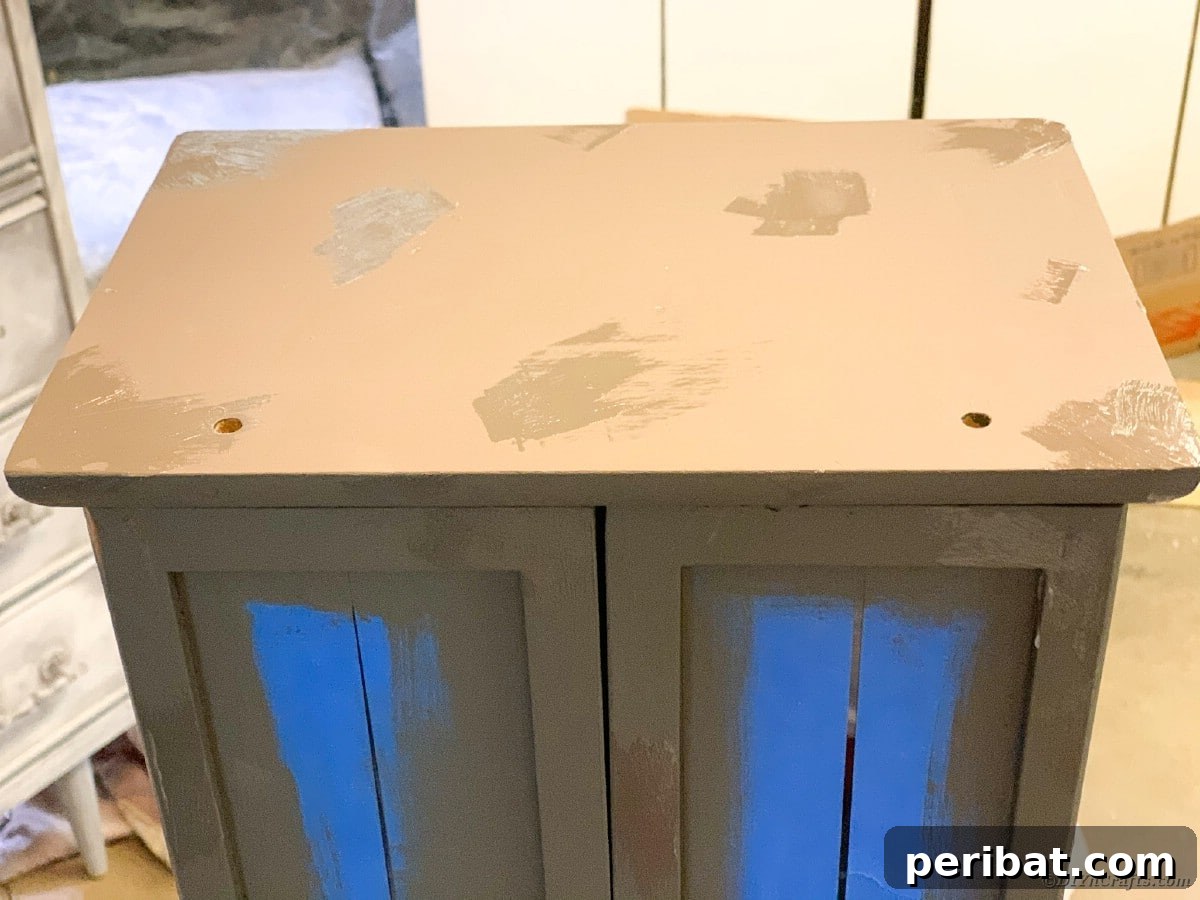 Applying the top coat of chalk paint to the curio cabinet