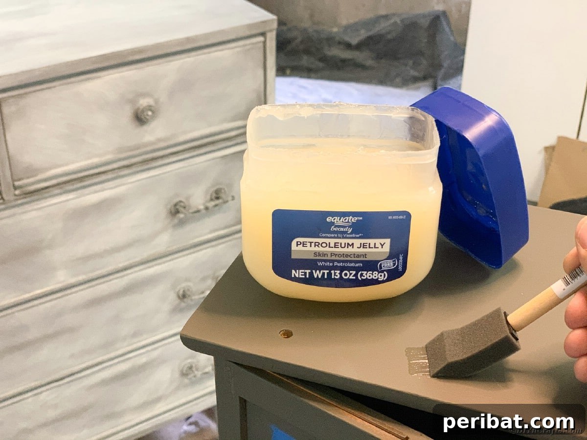 Applying petroleum jelly to curio cabinet for distressing effect