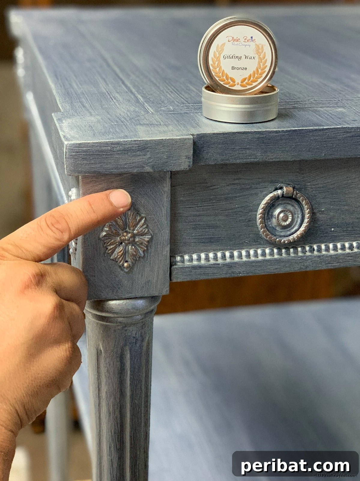 Applying bronze gilding wax to intricate details on the side table