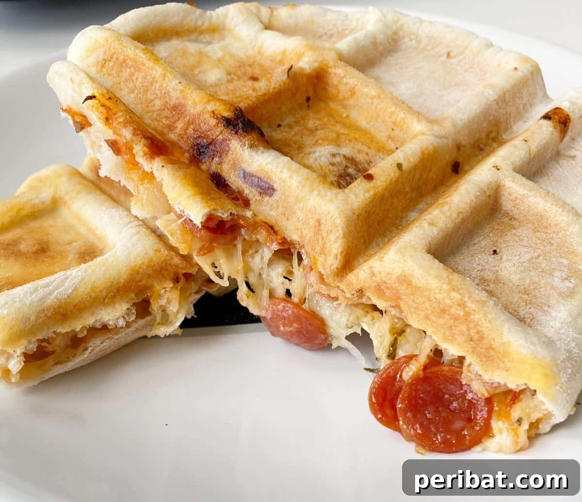 A savory calzone cooked in a waffle iron, with a perfectly golden and crispy crust, revealing a cheesy filling.